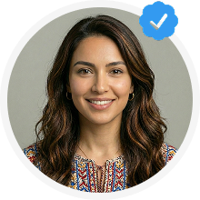 Smiling woman with long wavy dark hair wearing a colorful patterned top, with a blue verified checkmark badge overlay.